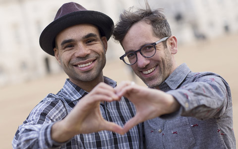 two men making heart symbol with hands smiling outside